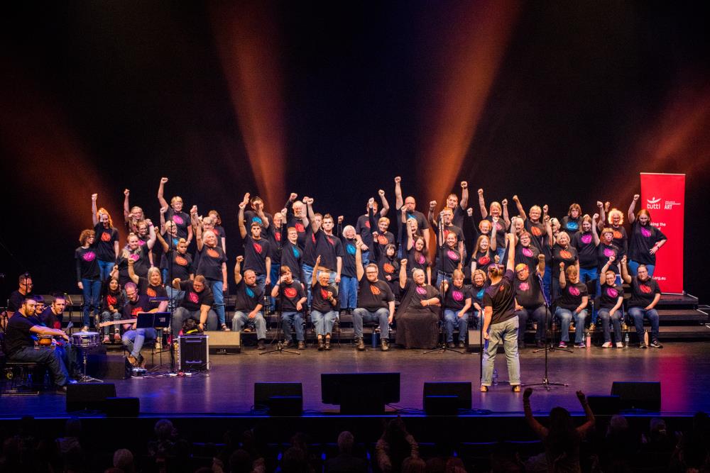 Band, choir and conductor on stage punching the air.